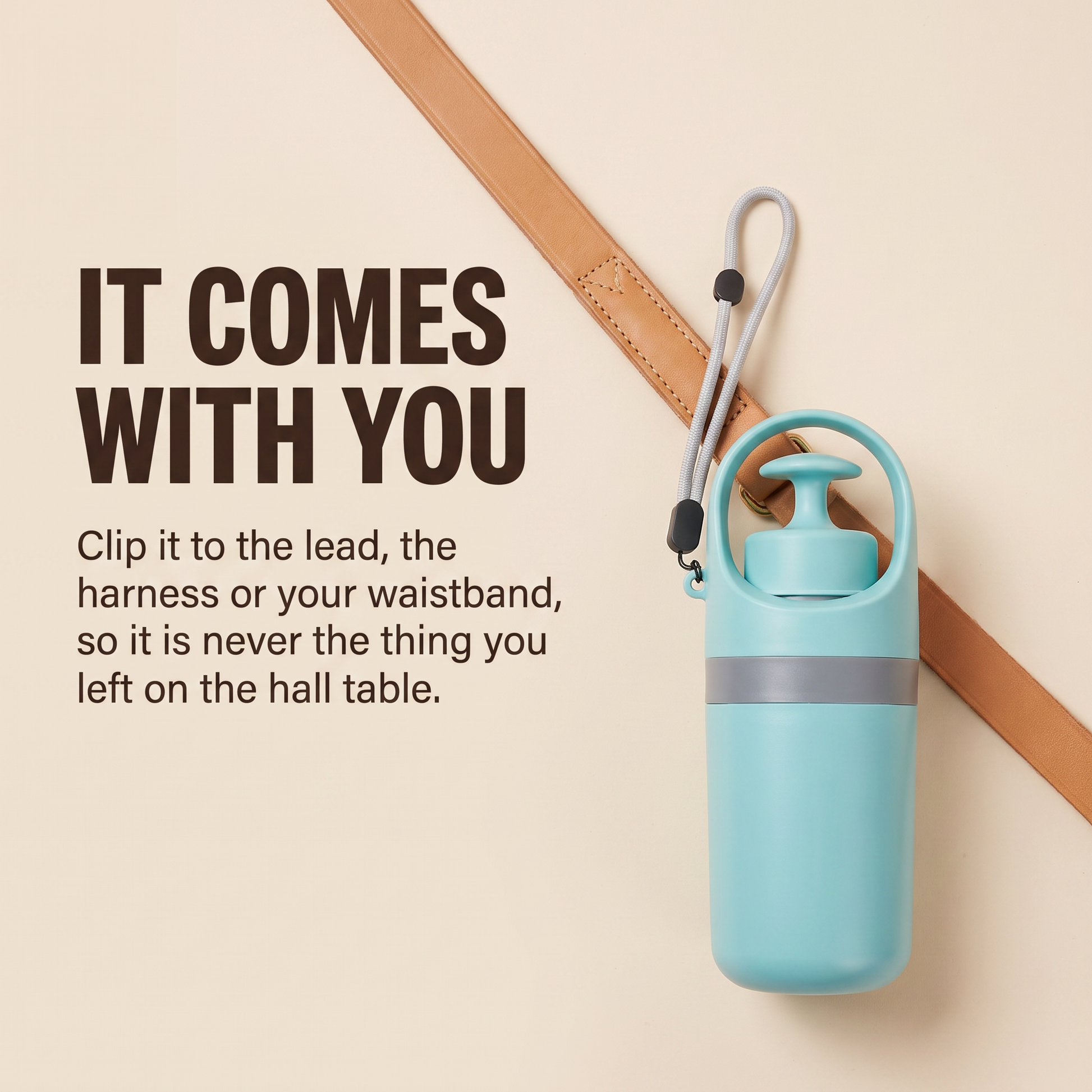 The pooper scooper clipped by its wrist strap to a tan leather dog lead